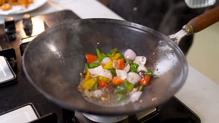 Bell peppers and onions being stir-fried in a wok.