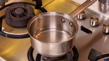 A saucepan with water being brought to a boil over medium heat.