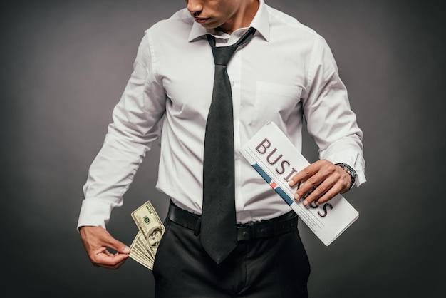 cropped view of wealthy african american businessman holding business newspaper and looking at