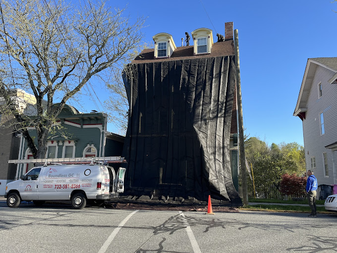 Boundless Roofing & Chimney team replacing the roof of a two-story house with an attic.