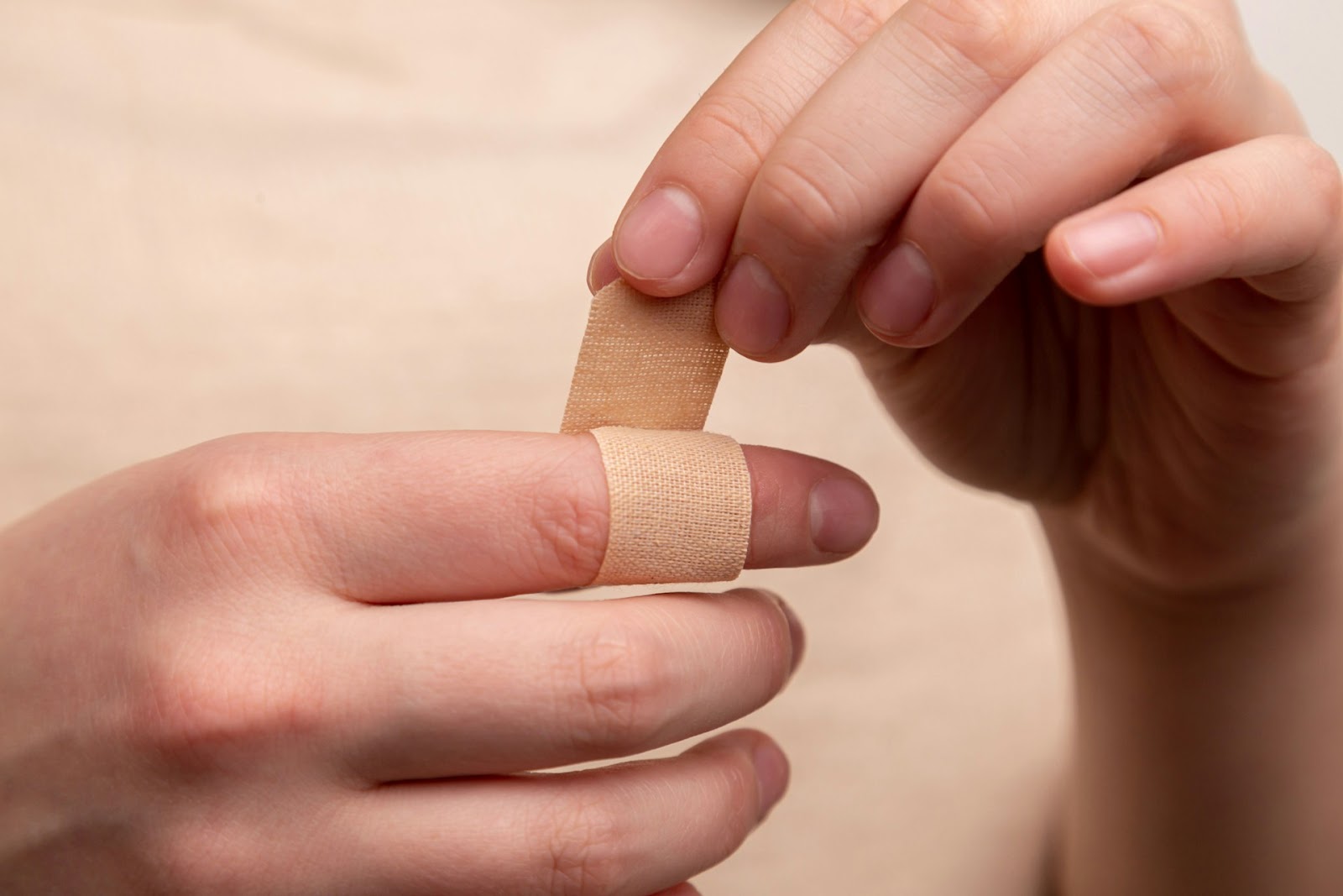 A woman putting bandage on her finger.