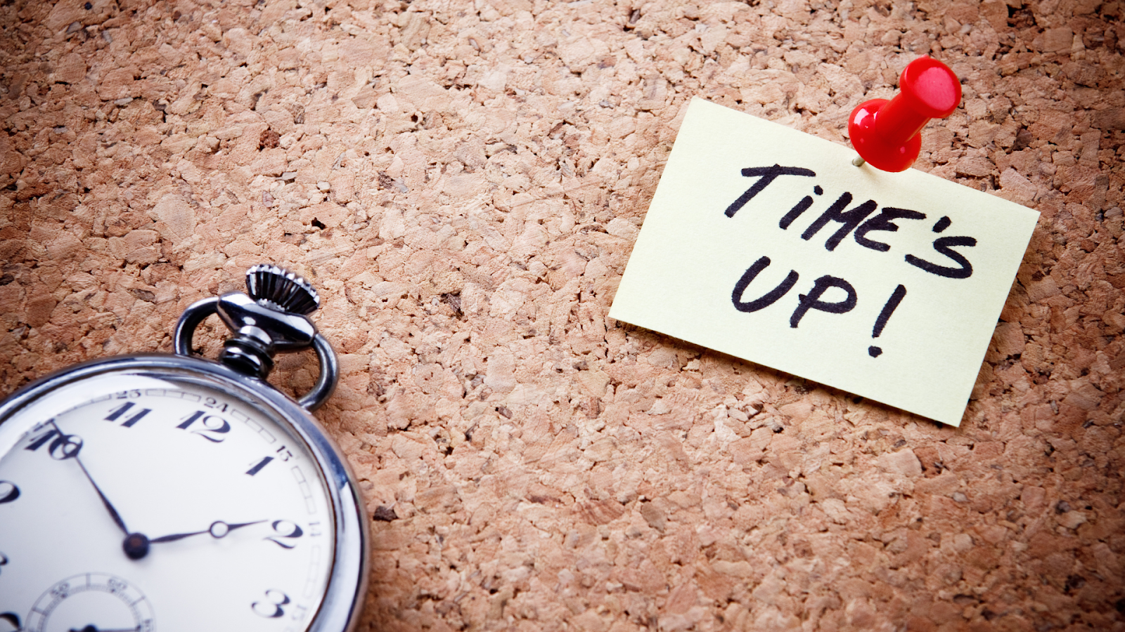 Clock and note on a corkboard that reads time’s up. 