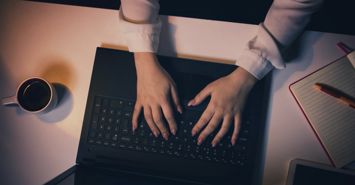 Person typing on a laptop keyboard, working on creating backlinks for SEO.