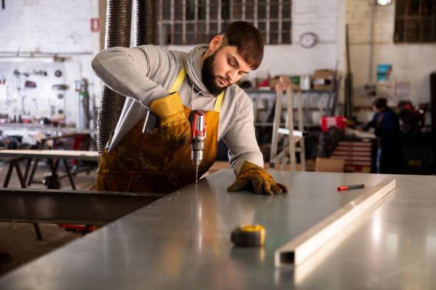 Man  engineer drilling metal sheet  in workshop Portrait of  man  engineer drilling metal sheet  in workshop sheet metal fabrication stock pictures, royalty-free photos & images