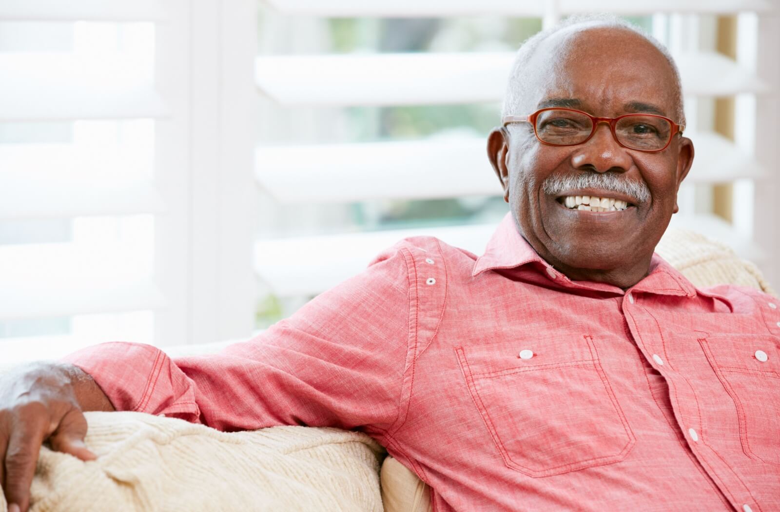 A happy older adult man sitting on a couch.