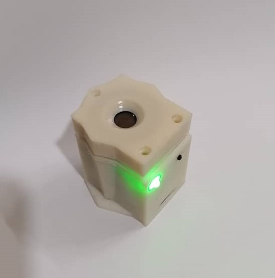 A small white object with a green light

Description automatically generated