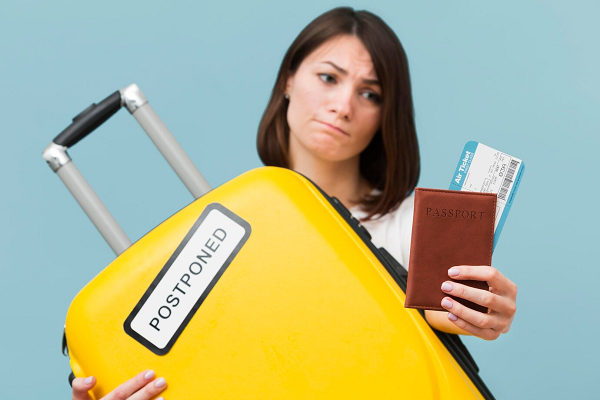 Woman with passport and yellow luggage | FintechZoom