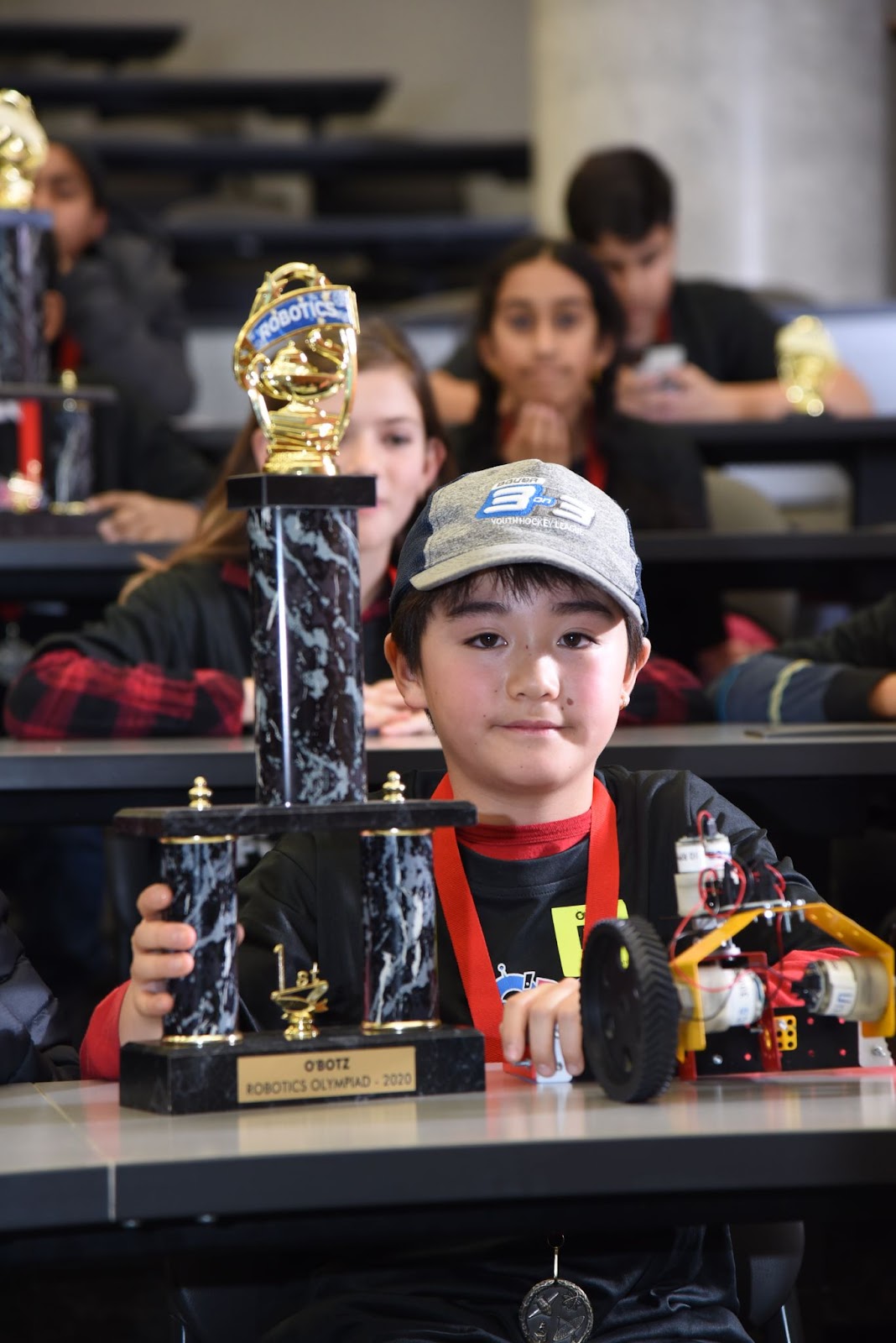 A student of OBotz holding the robotics olympiad trophy.