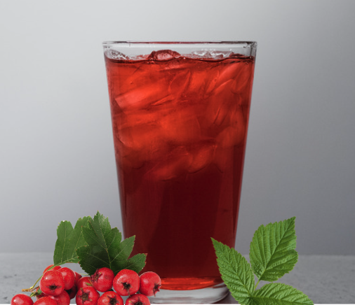 A tall glass of red Hawthorn berry iced tea with hawthorn berries and raspberry leaves next to it