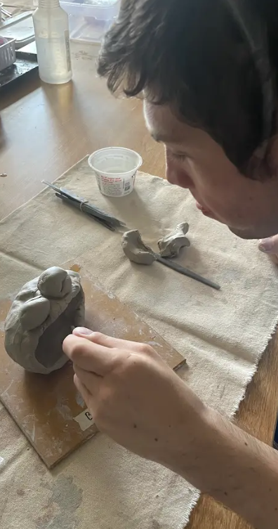 image of a student putting finishing touches on a clay project