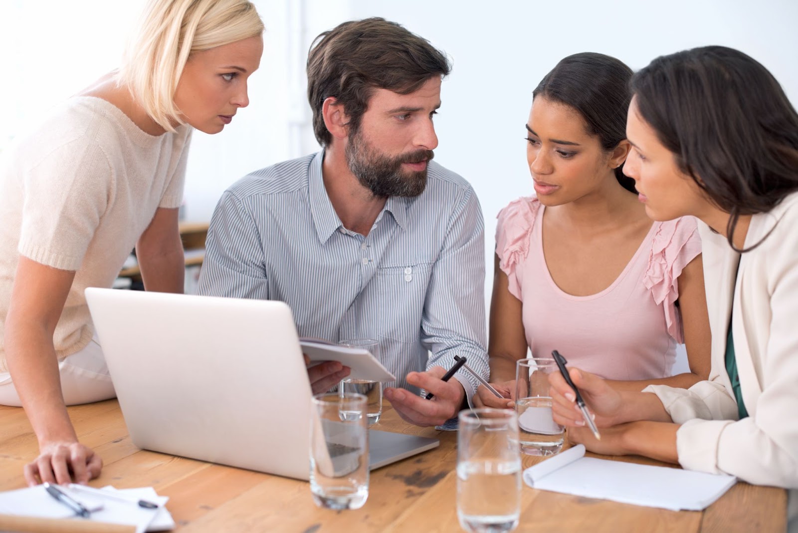 A group of consultants gather around a laptop to discuss design choices.