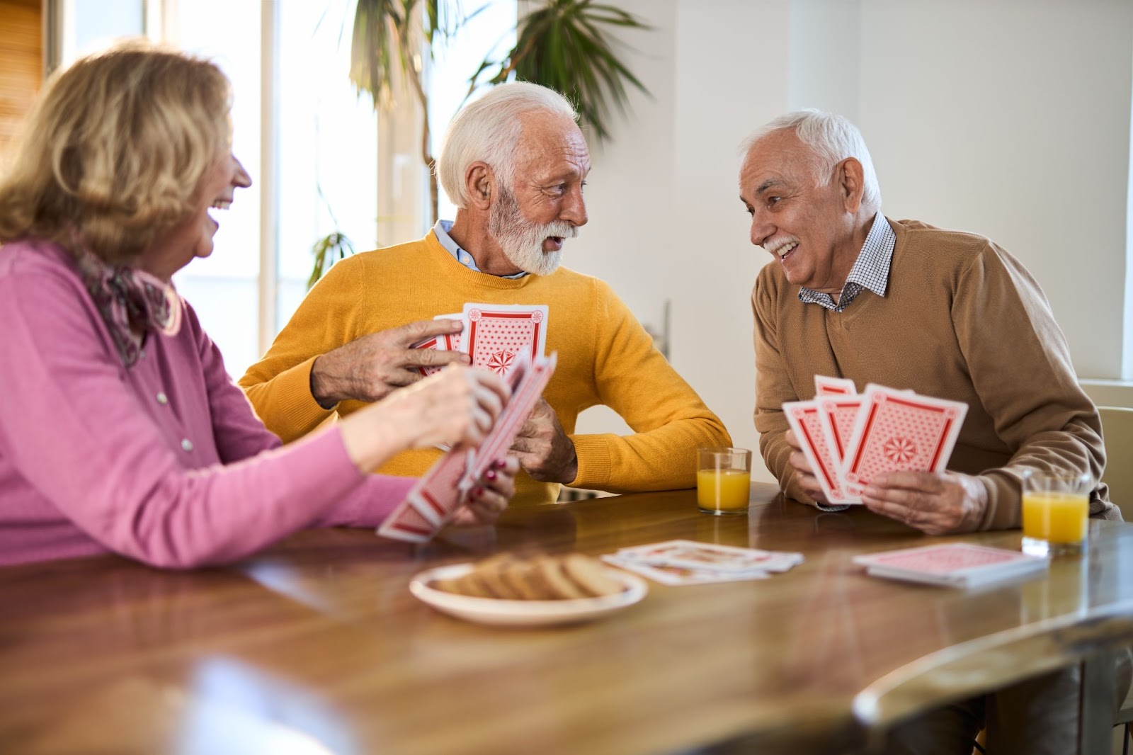 group of seniors playing cards at a kitchen table in assisted living