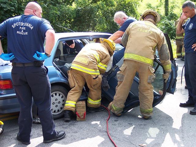 Firefighters helping another person get into a car</p>
<p>Description automatically generated