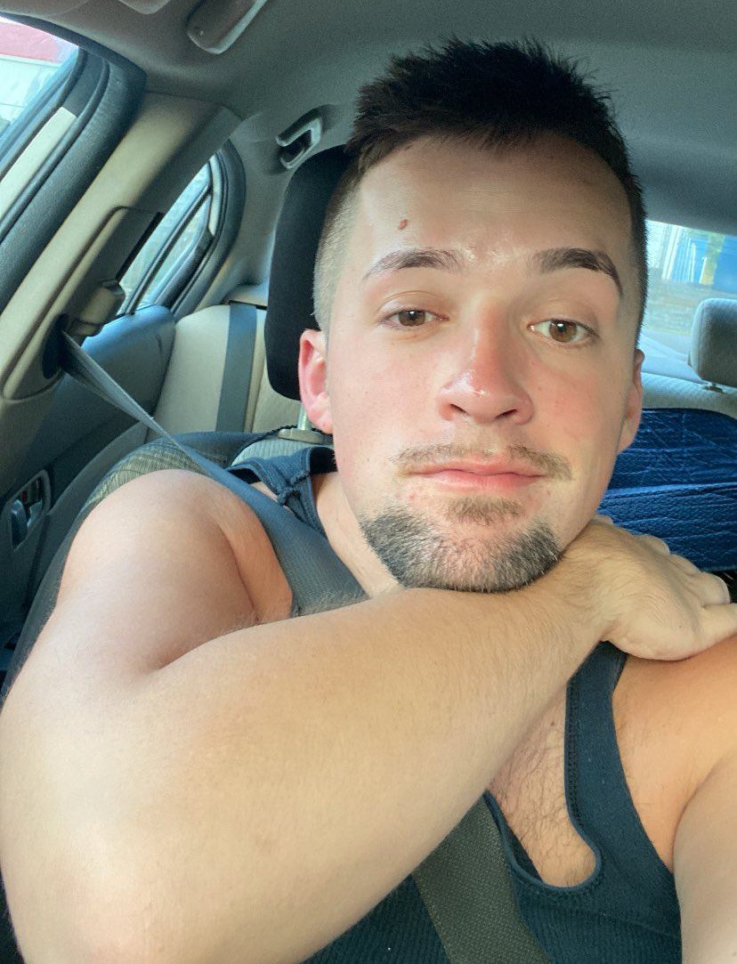 The Satyr Boy posing in a tank top in the car smirking for gay iphone selfie