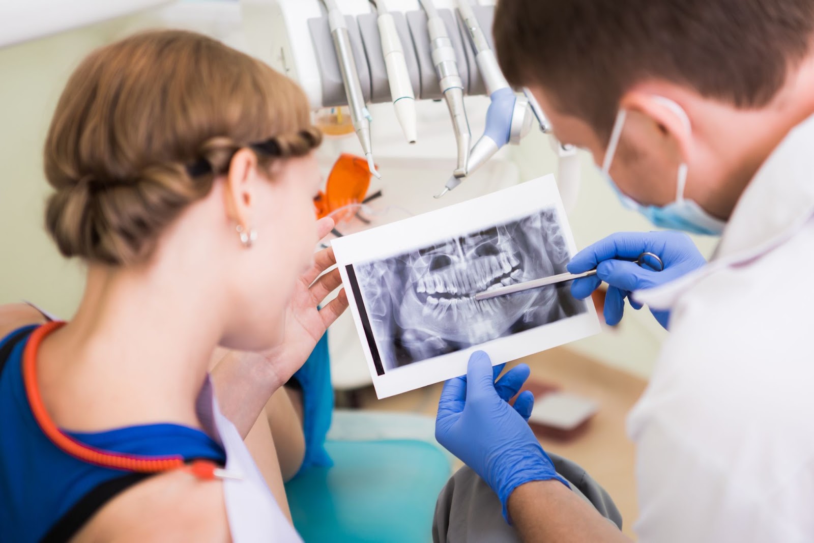 A dentist reviews dental X-rays with a female patient.