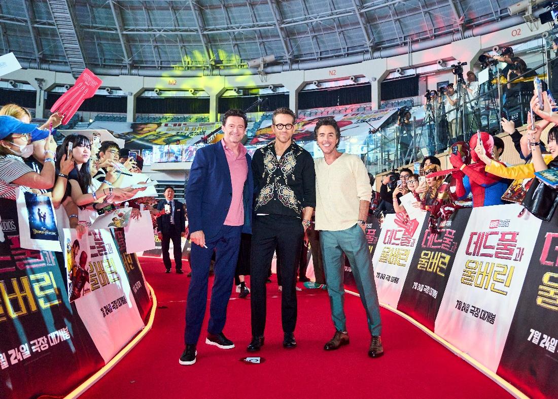 A group of men standing on a red carpet

Description automatically generated