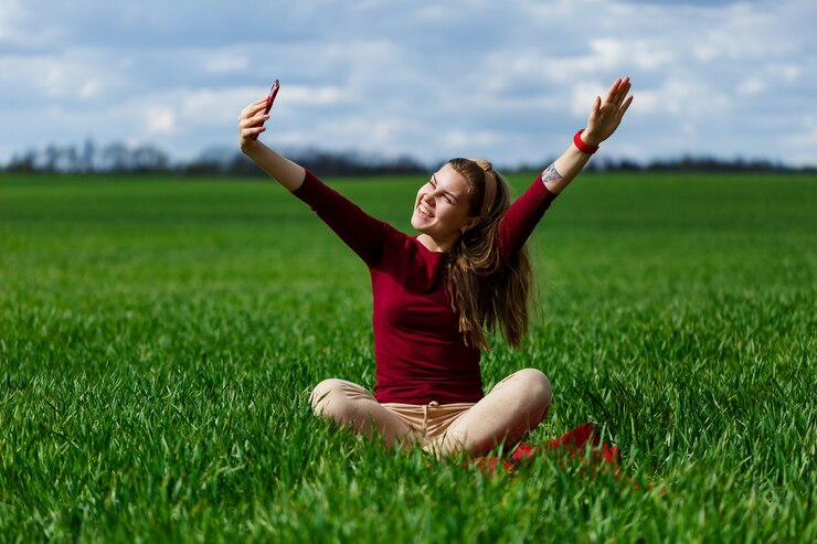 Young beautiful woman taking a selfie sitting on grass