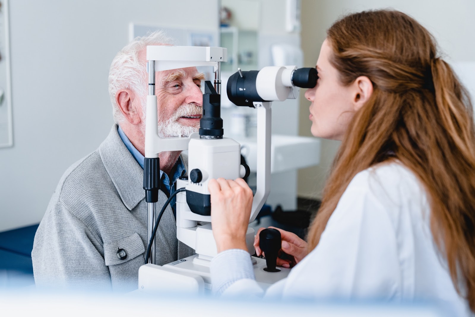 An optometrist examines an older man's eyes for cataracts after surgery at an eye clinic.