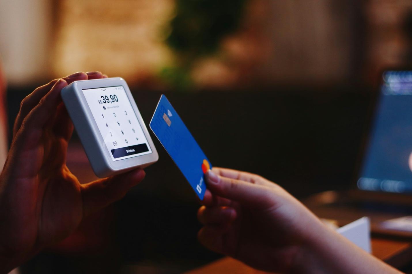 A person holding a credit card and a device

Description automatically generated