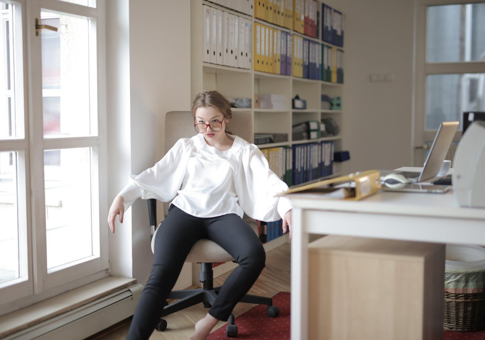 Bossy female employee in formal wear sitting on chair in workplace demonstrating frivolous behavior