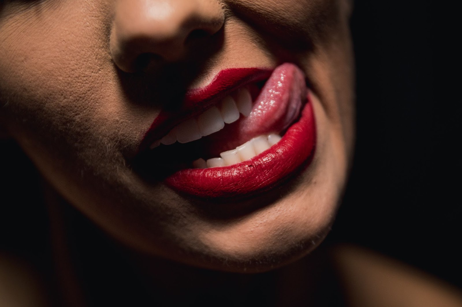 Shot of a woman's seductive lips with red lipstick and tongue out
