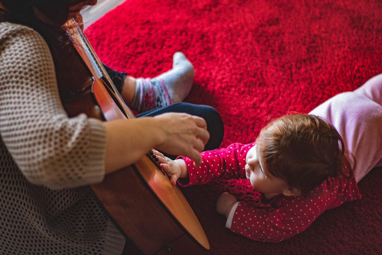 A person playing a guitar with a baby

Description automatically generated