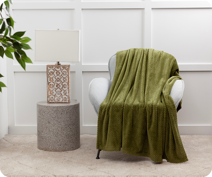 Our green Chevron Plush Throw in Green shown styled on an armchair.