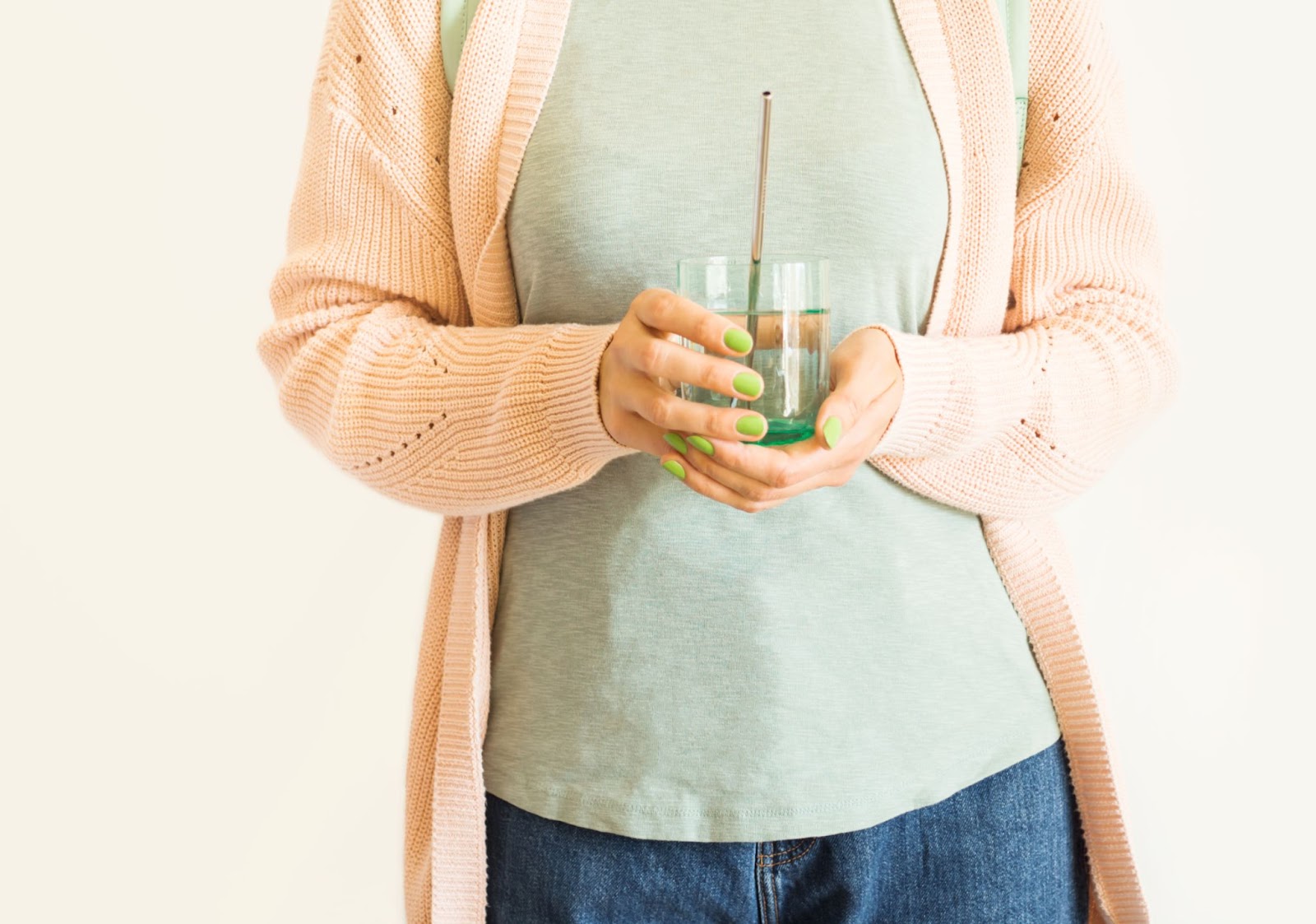 femme tenant un verre d'eau contenant une paille