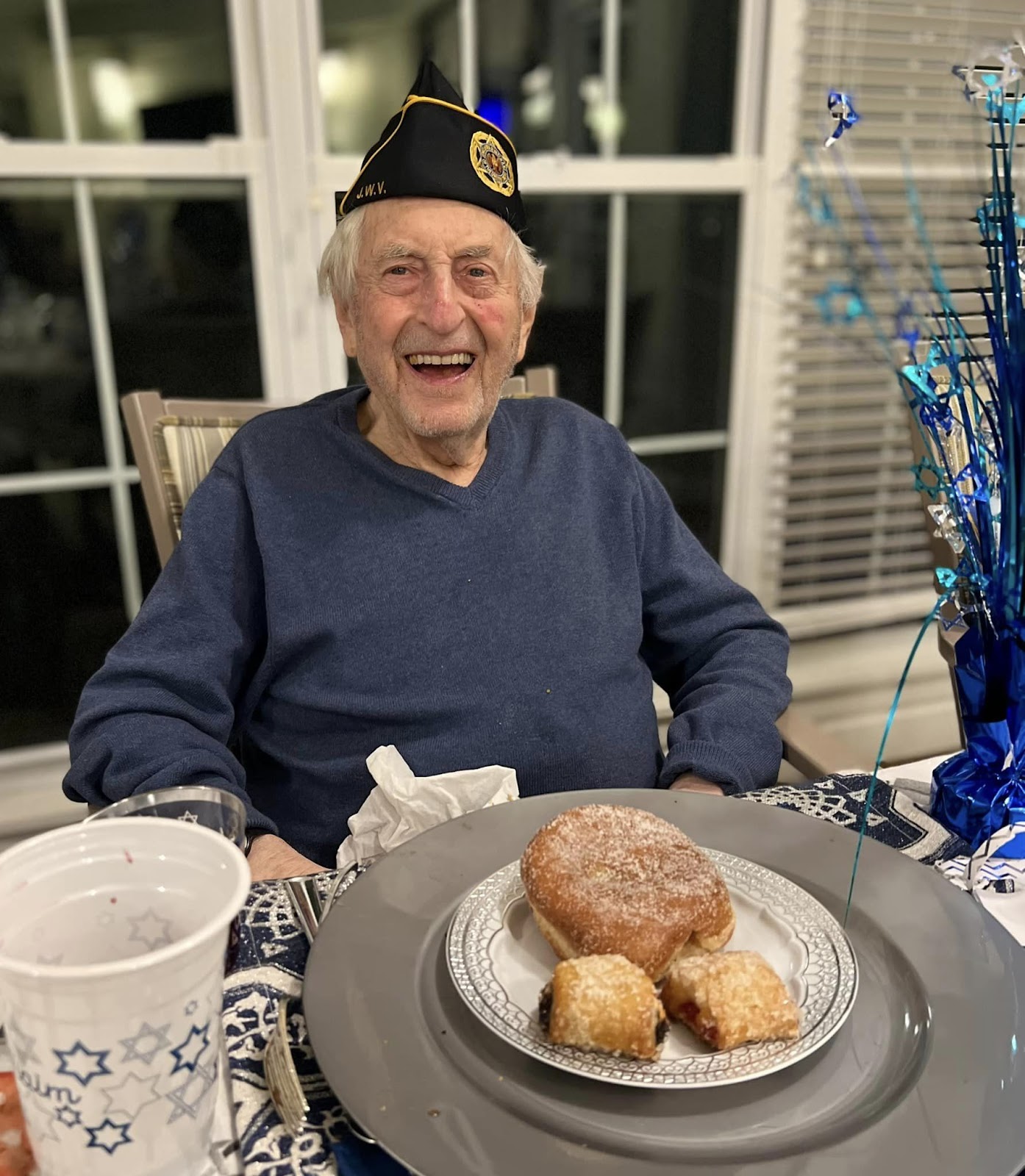 A senior smiling with a plate of sweets in front of him and receiving the 5 levels of care in assisted living