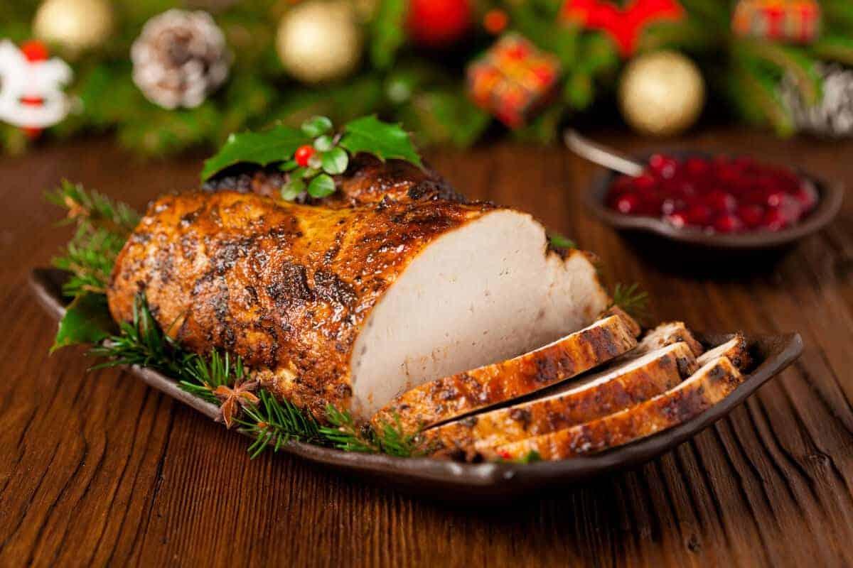Muschiă de porc afumată și feliată pe o masă cu aspect festiv