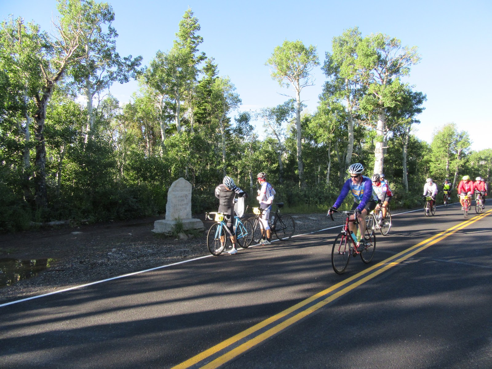 Cyclists on bikes next to stone sign during Monitor Pass East portion of death ride