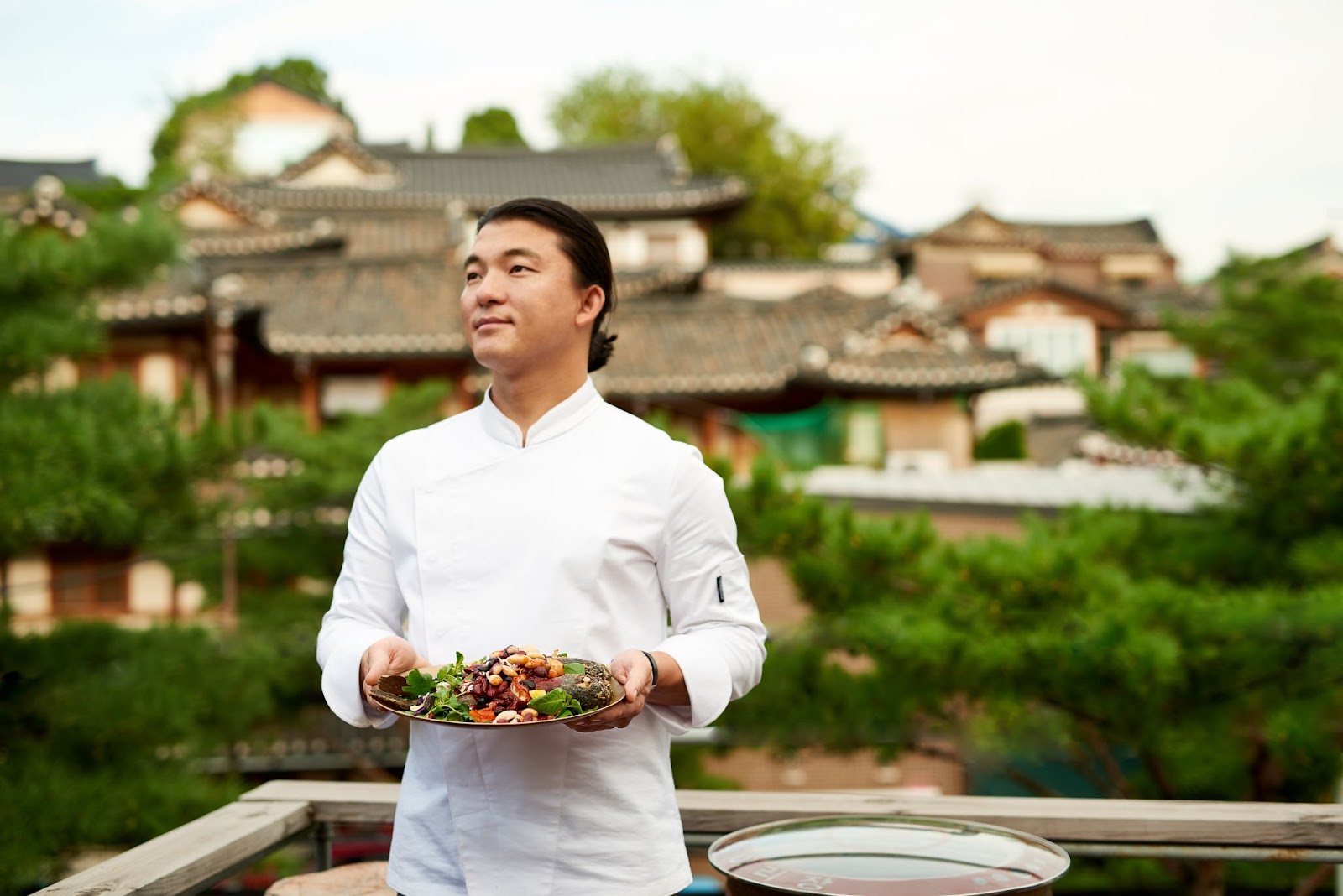 Chef Yoo presents a colorful dish in a white chef's coat