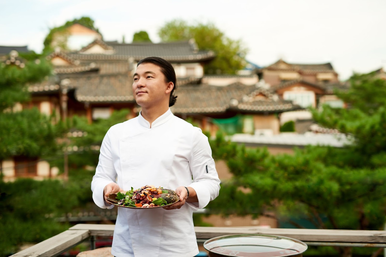 Chef Yoo presents a colorful dish in a white chef's coat 