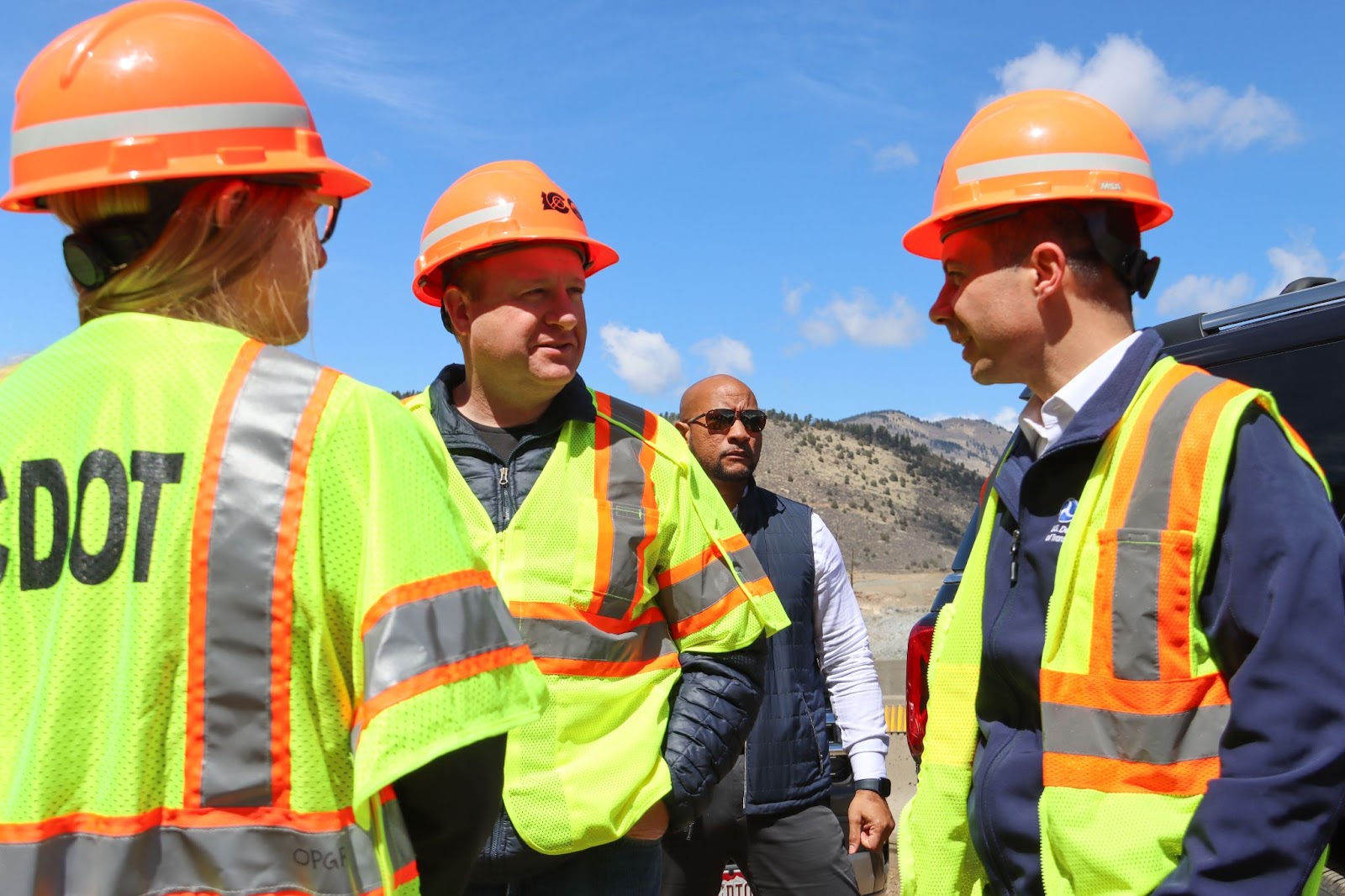 Governor Polis, Department of Transportation Secretary Pete Buttigieg, and Colorado Department of Transportation Director Shoshana Lew speak while at the Floyd Hill construction site.