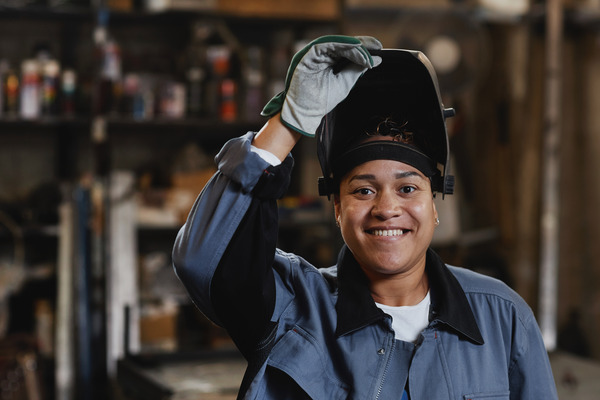 Smiling welder in an industrial setting, embodying the positive perks of the profession