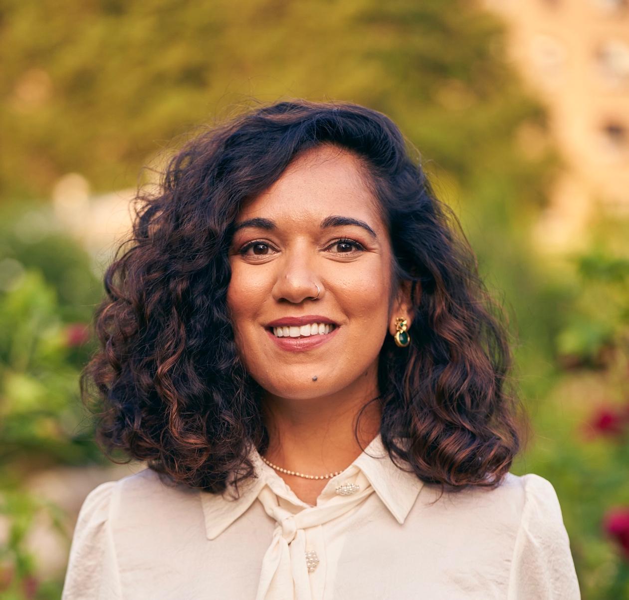 A person with curly hair smiling

Description automatically generated