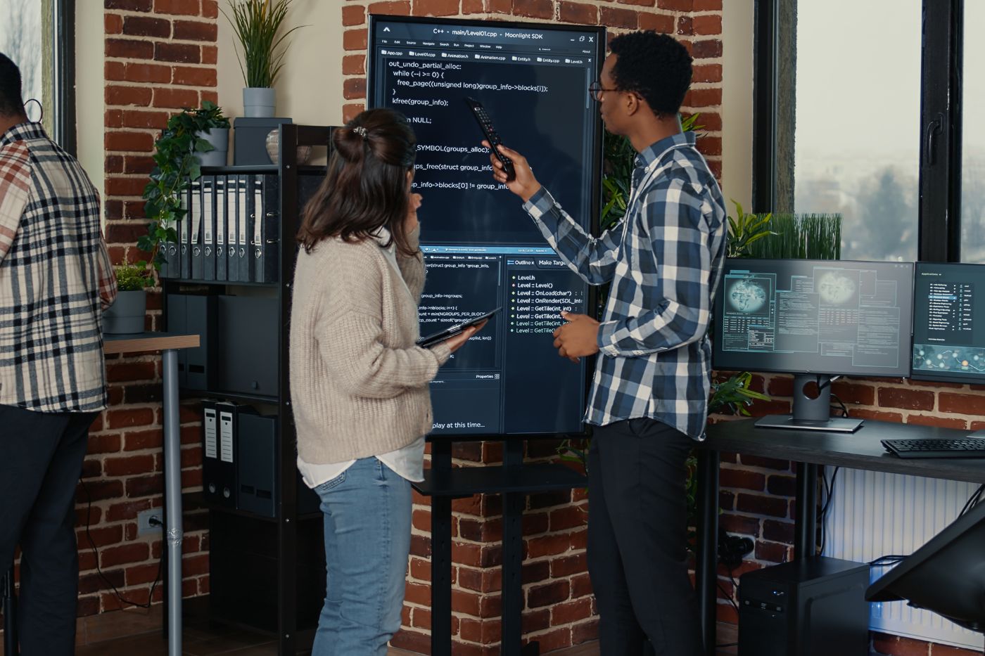 Two people standing in front of a computer screen.