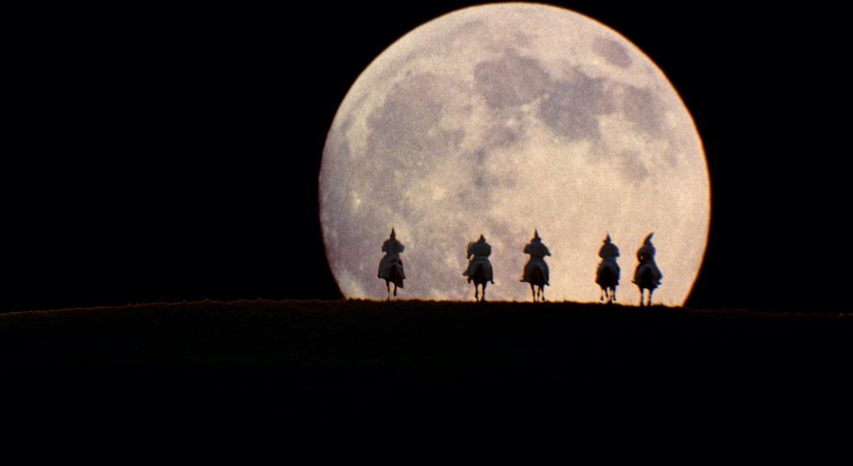 A group of people on horses in front of a full moon<br><br>Description automatically generated with medium confidence