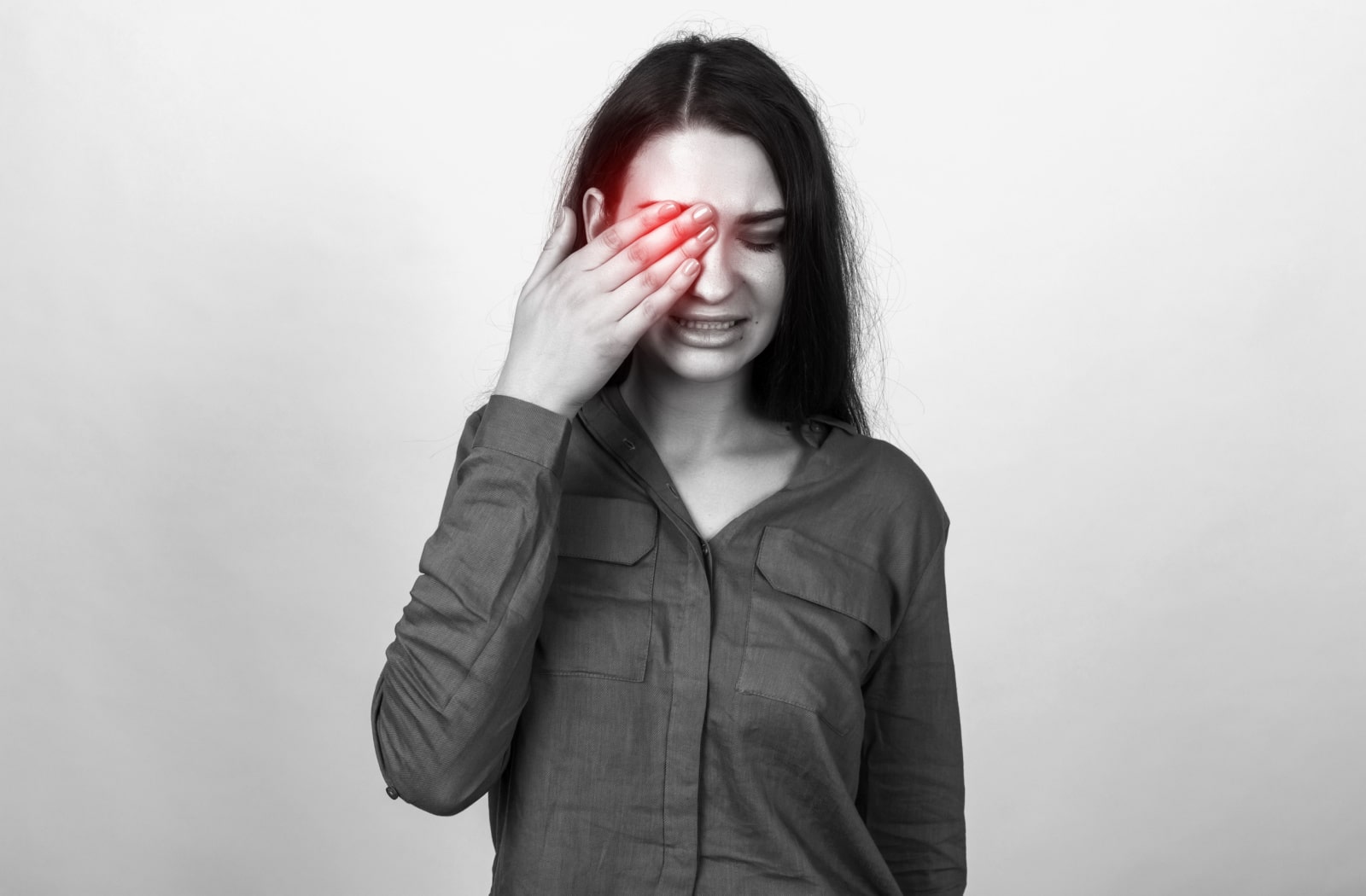 A woman holding her right hand over her eye due to eye pain