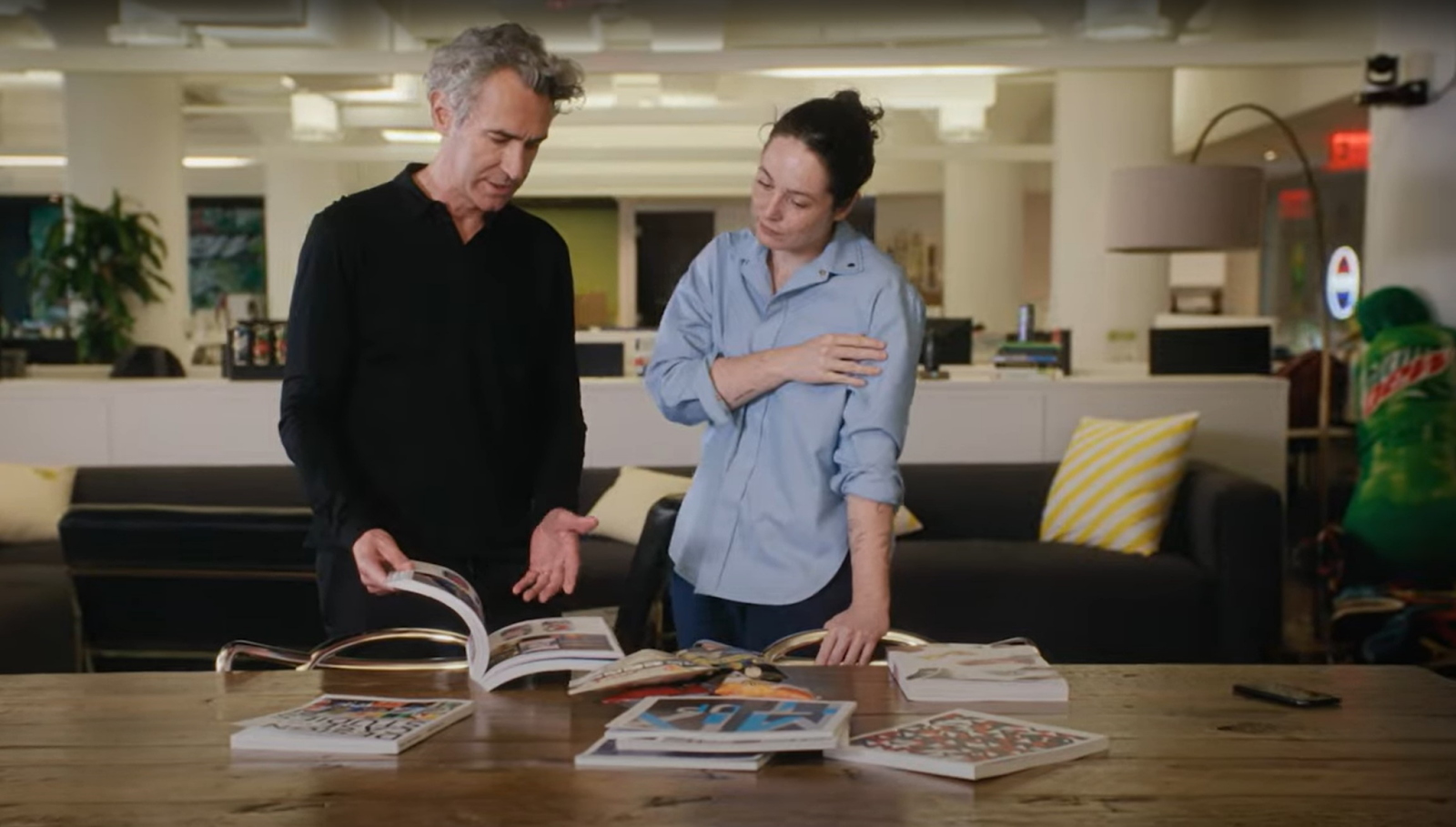 Two PepsiCo colleagues chat while looking at a design book together.
