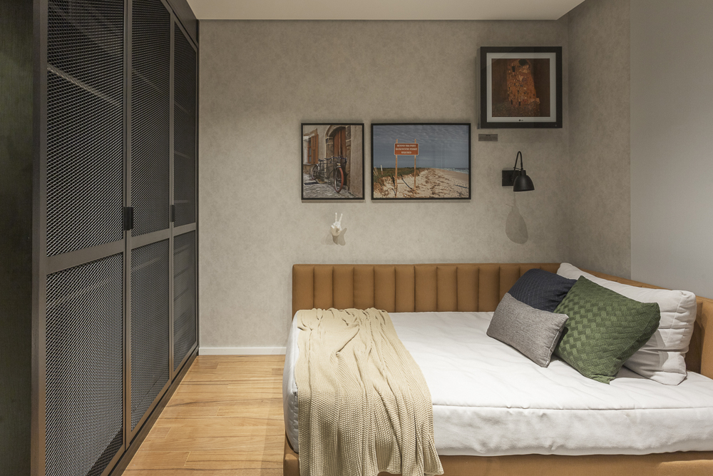 Foto de um quarto de casal decorado com uma cama e um guarda-roupa na cor preta, paredes em tons de bege.