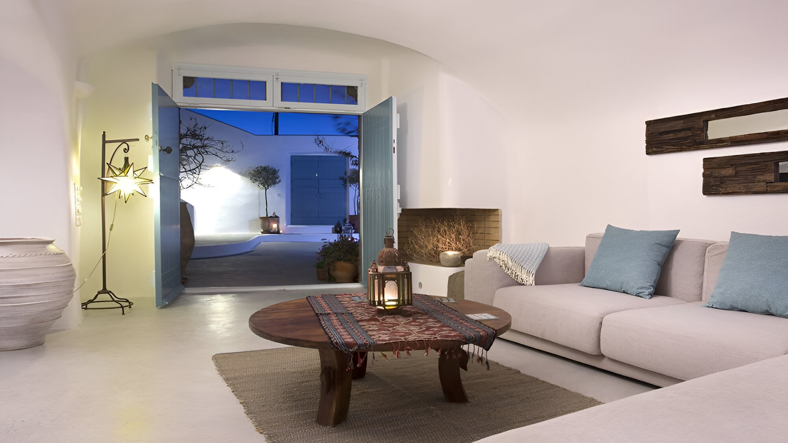 A living area with couches and a wooden round table of a house in Santorini 
