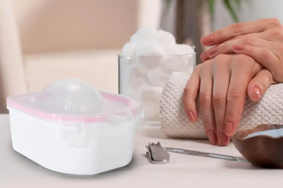 An image of hand, manicure bowl, and nail cutter