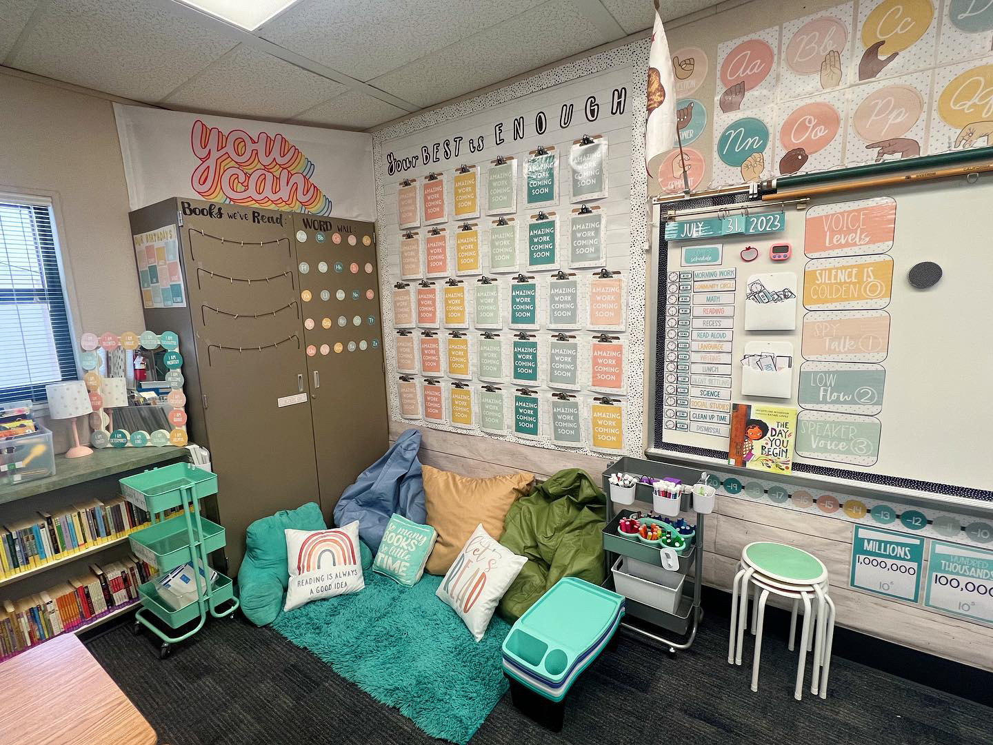 This image shows a classroom library with a rug and pillows thrown together on the floor. 
