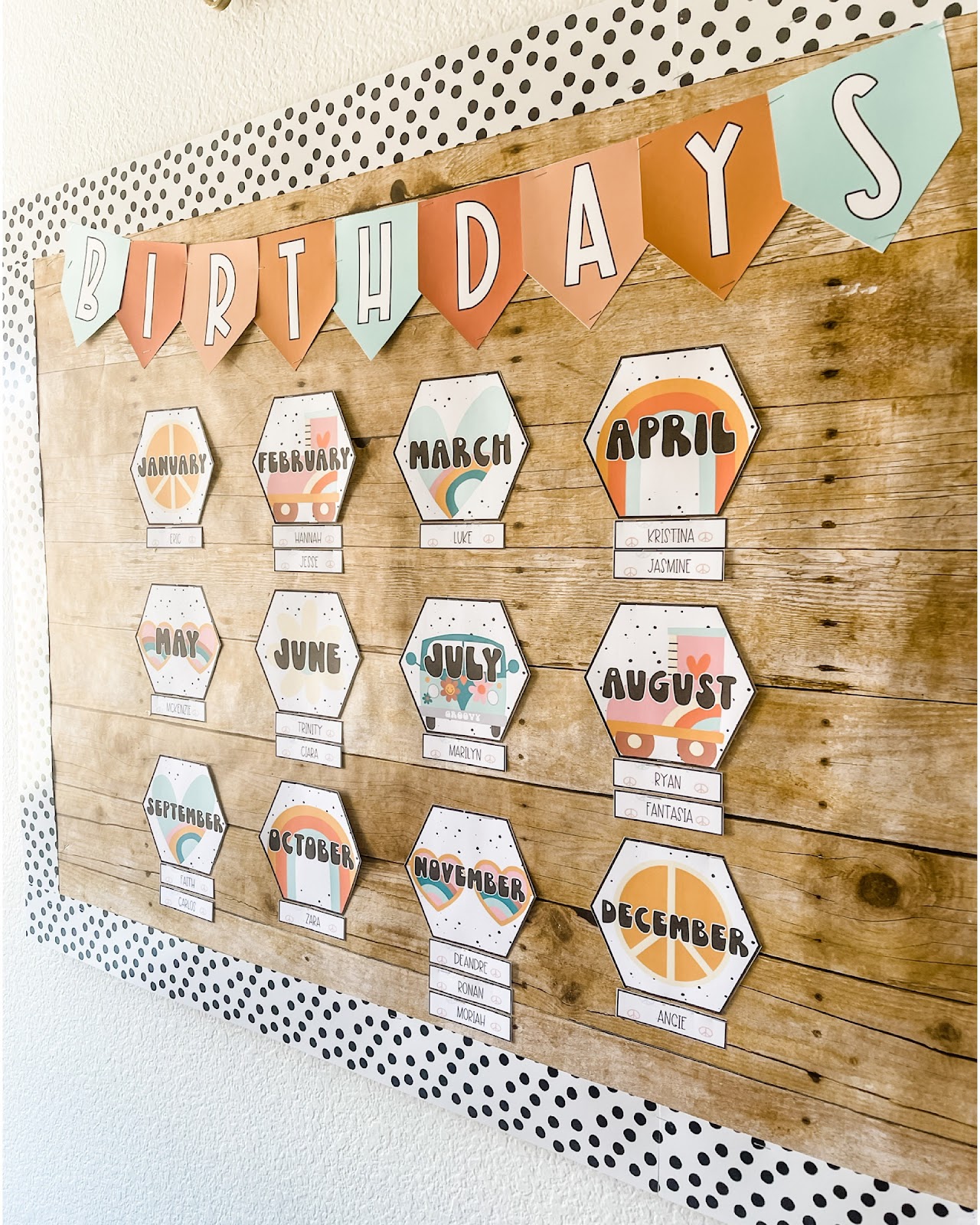This image shows a bulletin board display with a heading reading "Birthdays". There is a card for each month of the year with smaller cards for student names underneath. The month cards are decorated with fun, retro images like roller skates and peace signs. 