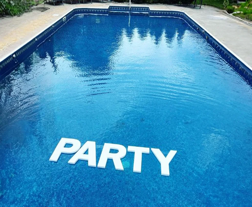 a pool with floating foam letters that spell out "PARTY"