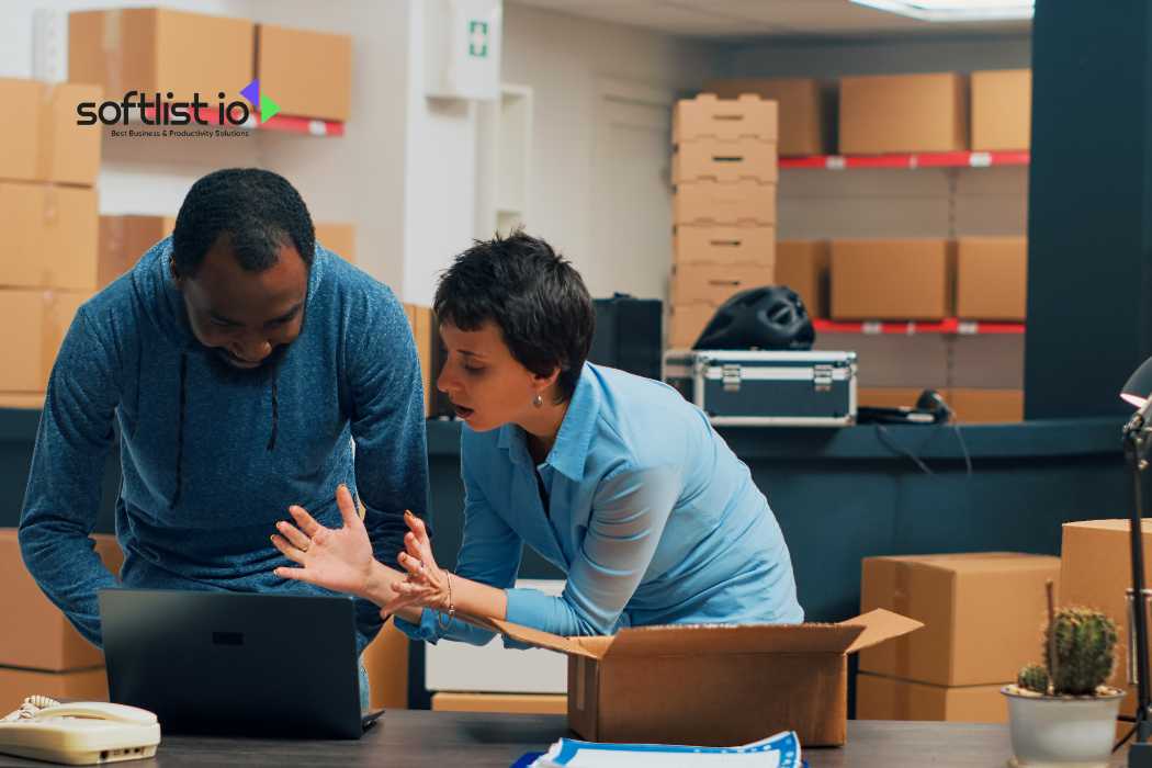 Two people discussing logistics with a laptop in a warehouse with boxes