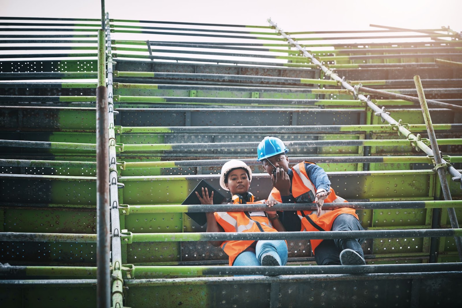 A young man and woman working at a construction site with a safety helmet and a jacket.