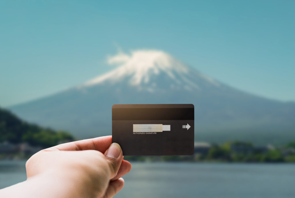 Person holding a credit card with backdrop of a mountain