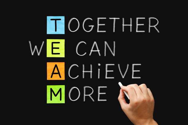 TEAM Together We Can Achieve More Hand writing TEAM Together We Can Achieve More with white chalk on blackboard. Teamwork, synergy or cooperation business concept. Building a Winning Team  stock pictures, royalty-free photos & images